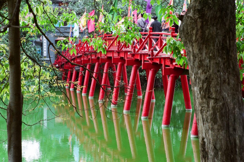Red architectural details beside green water and trees