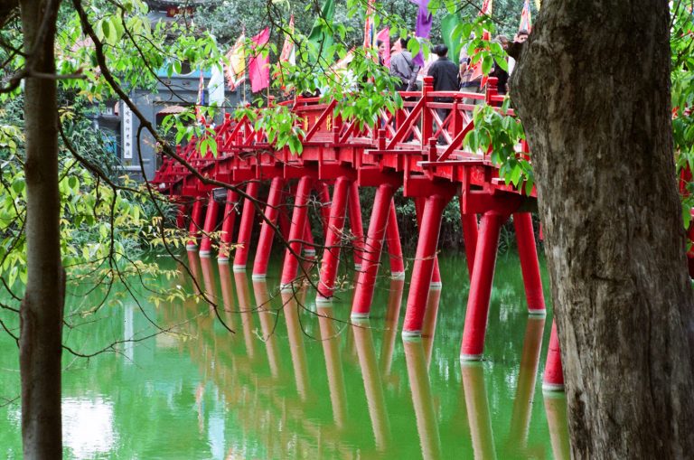 Red architectural details beside green water and trees